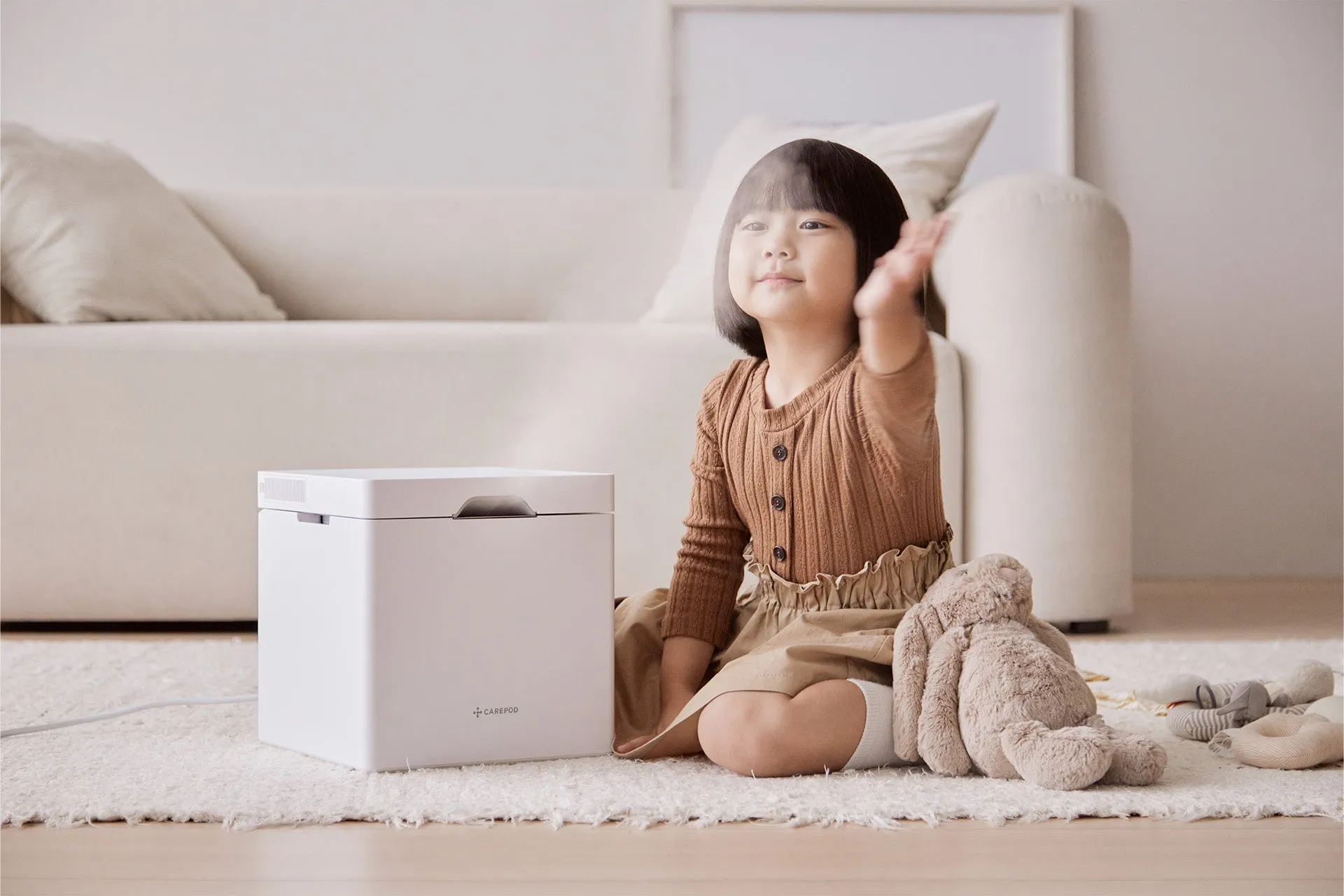 小さな女の子が加湿器のそばに座っている画像