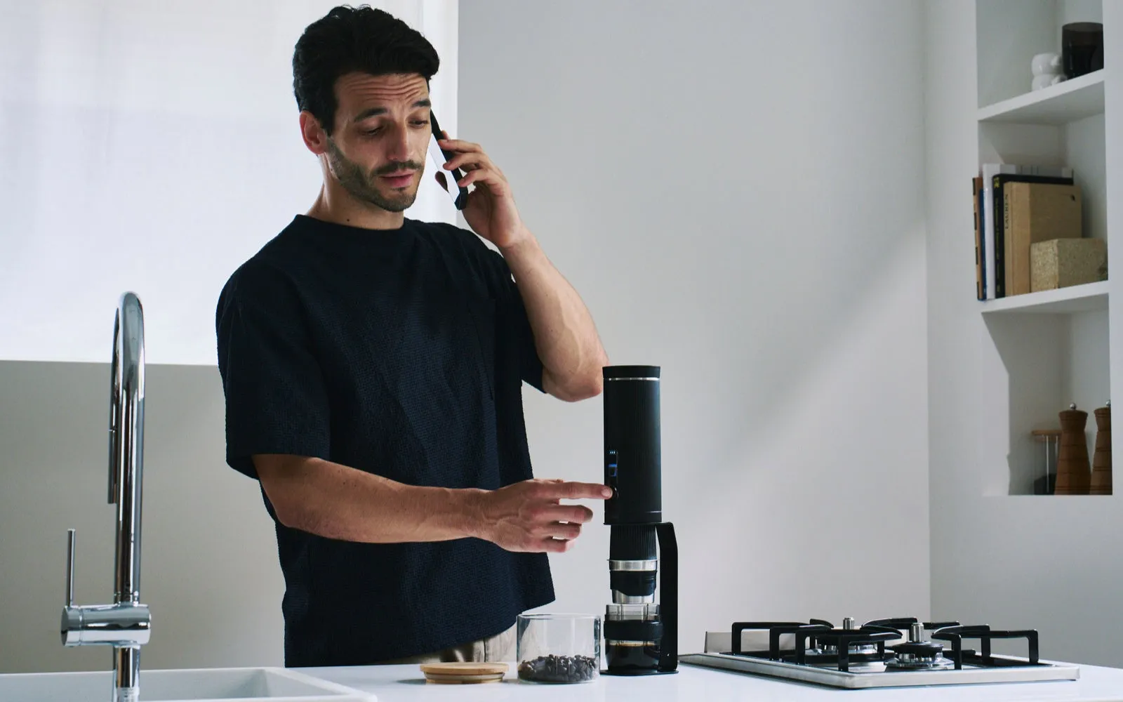 男性が電話をしながらコーヒーメーカーの電源を入れている様子