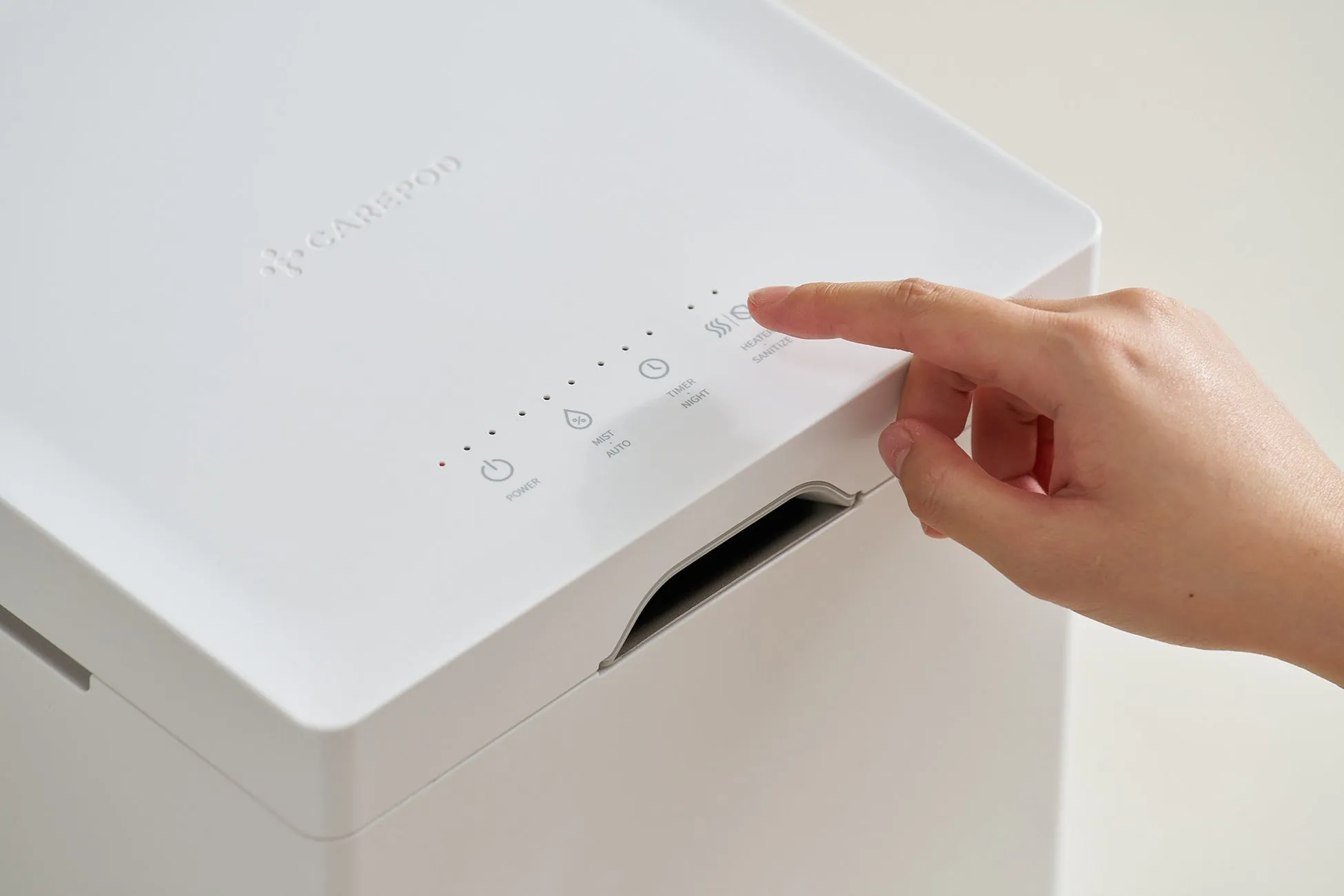 白い家電製品の操作パネルに指が触れている様子