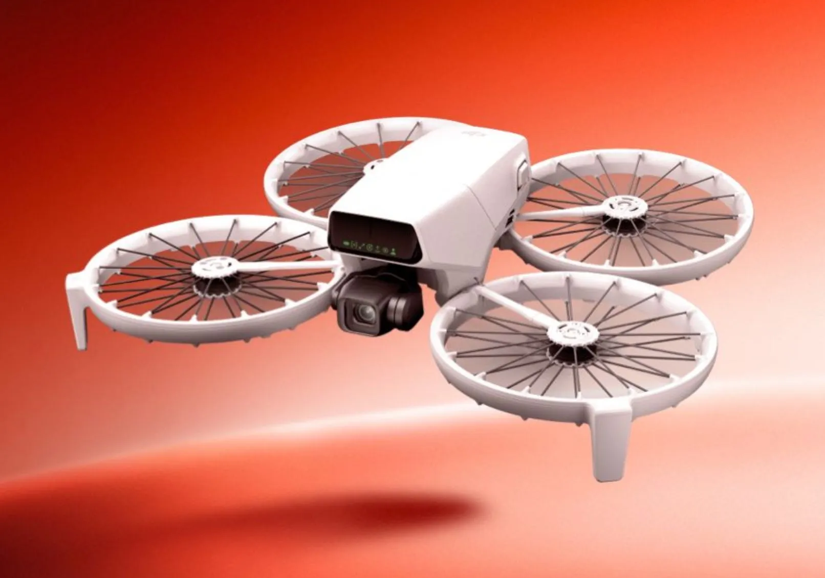 白いドローンが赤色の背景に配置されています。ドローンは4つのプロペラがあり、中央にカメラが設置されています。