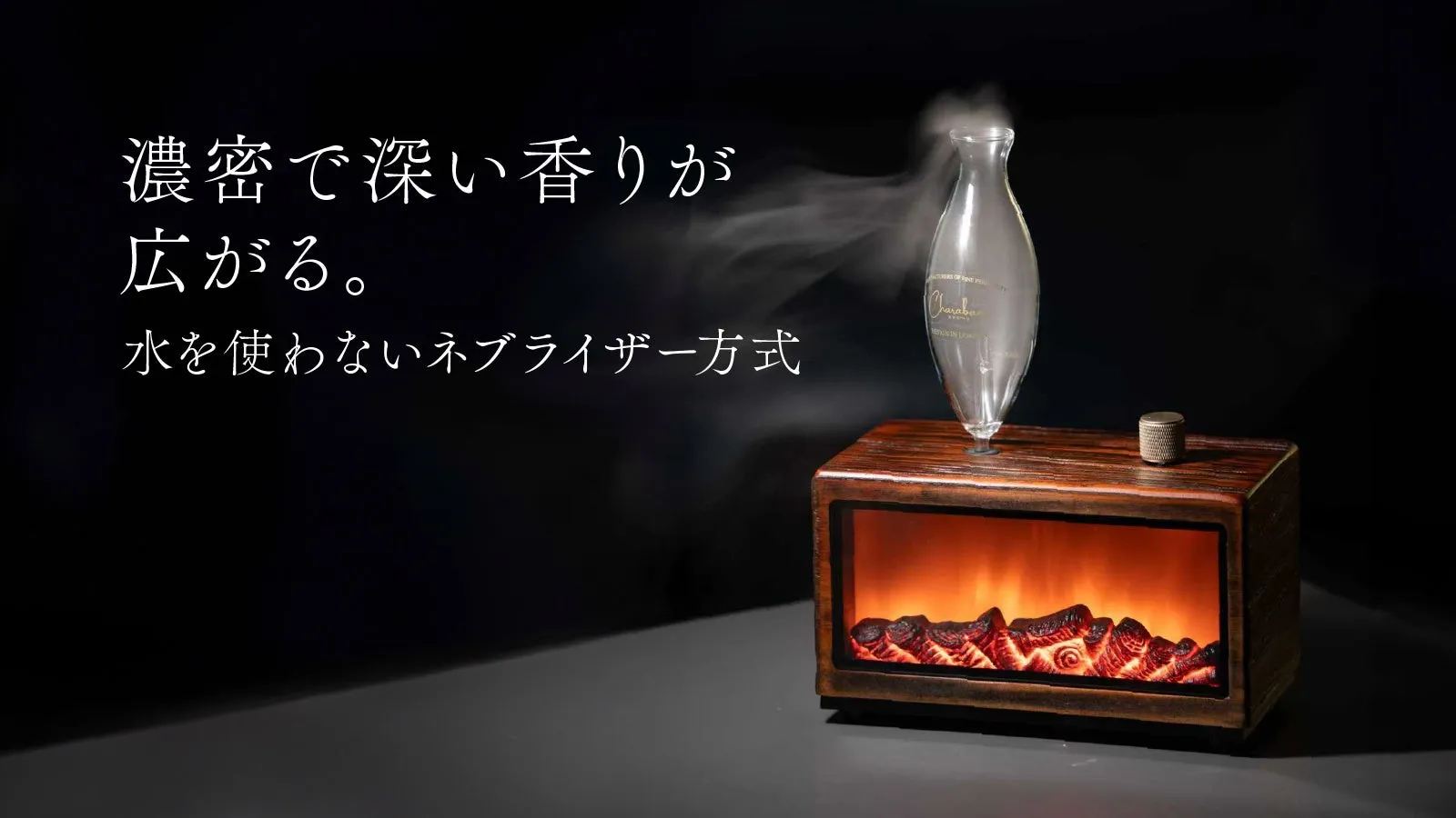 暖炉を模したアロマディフューザーの画像。ディフューザーから香りのミストが立ち上り、濃厚で深い香りが広がる様子が表現されている。水を使わないネブライザー方式であると記載されている。