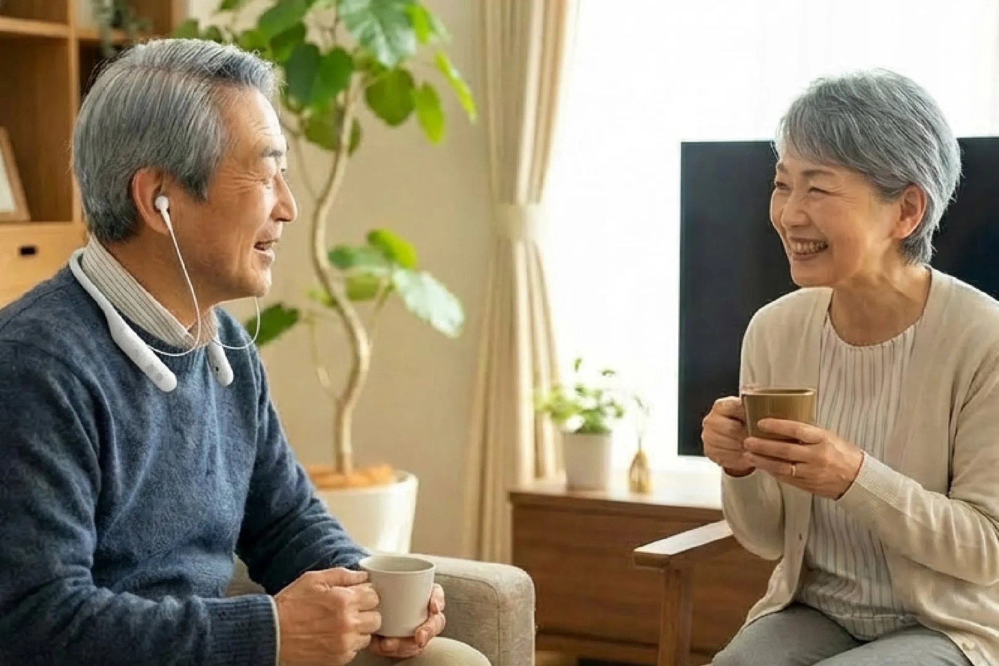 高齢の夫婦が自宅のリビングでくつろぎながら会話を楽しんでいる様子