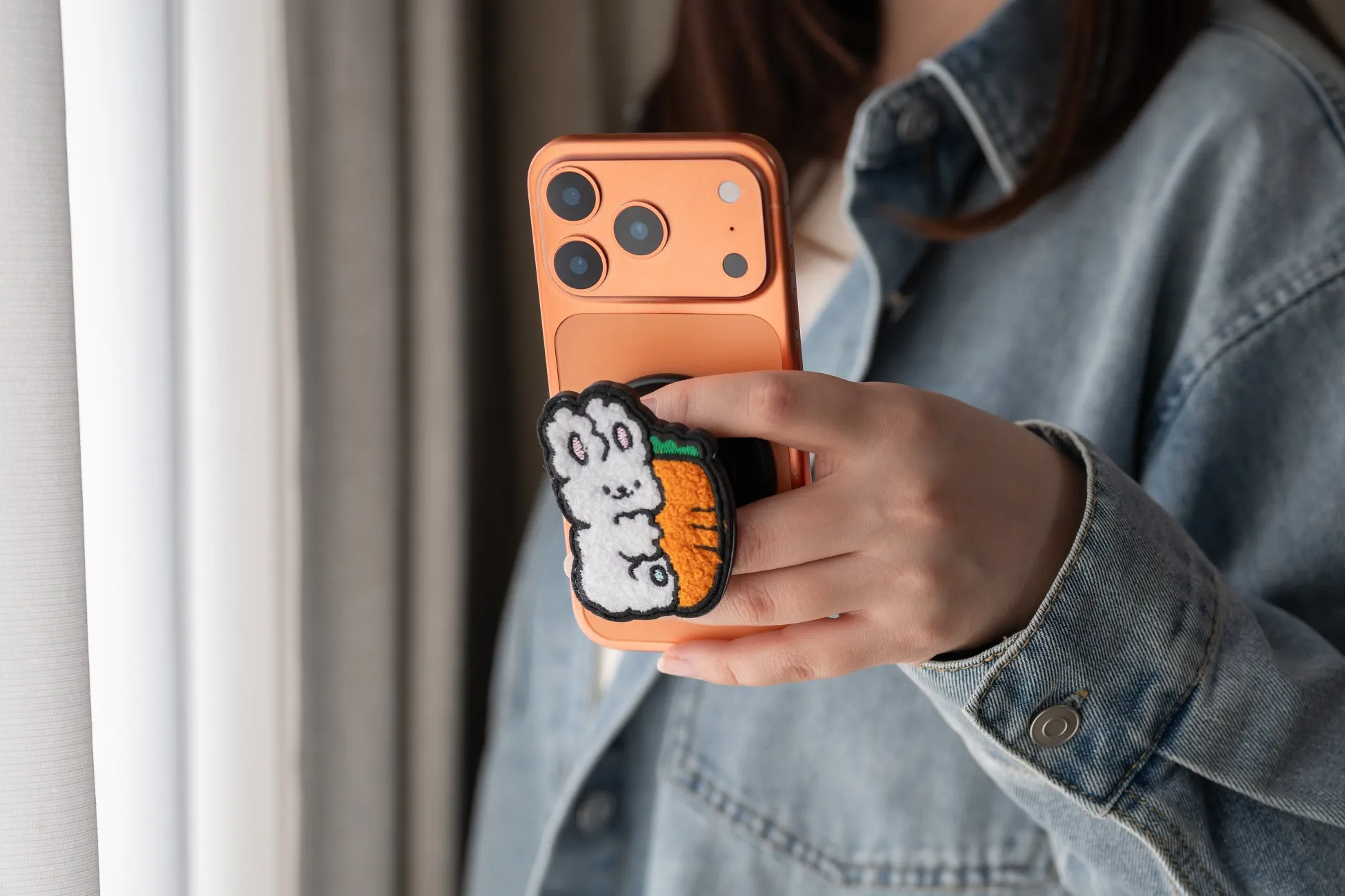 スマホを持った女性。スマホにはウサギとニンジンが描かれたスマホグリップが付いている。