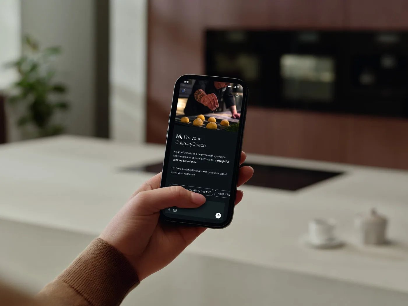 スマートフォンに表示されたクッキングアシスタントのアプリの画面。料理の画像が表示されており、アプリの説明文が書かれている。