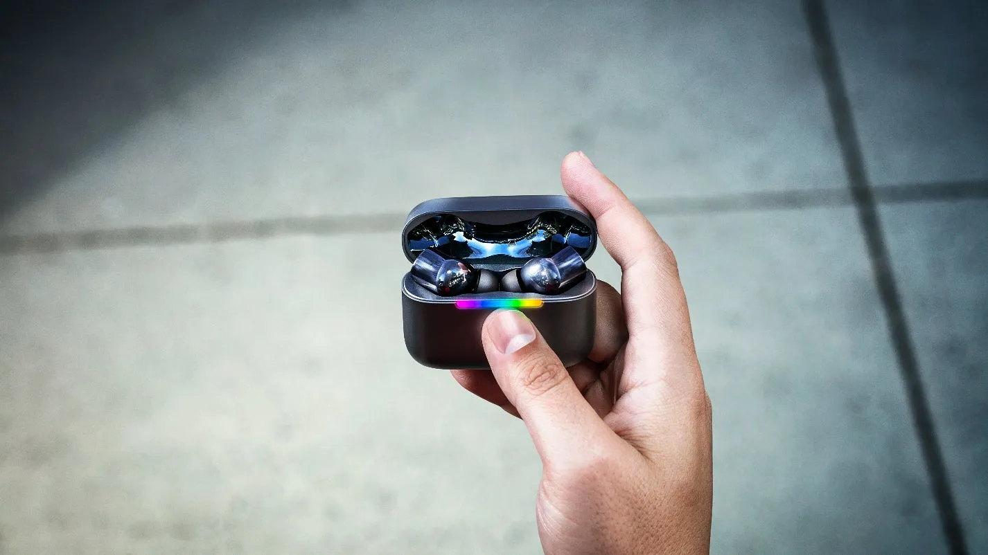 イヤホンケースを開き、カラフルなライトが点灯しているワイヤレスイヤホンを手のひらに乗せて撮影した写真。