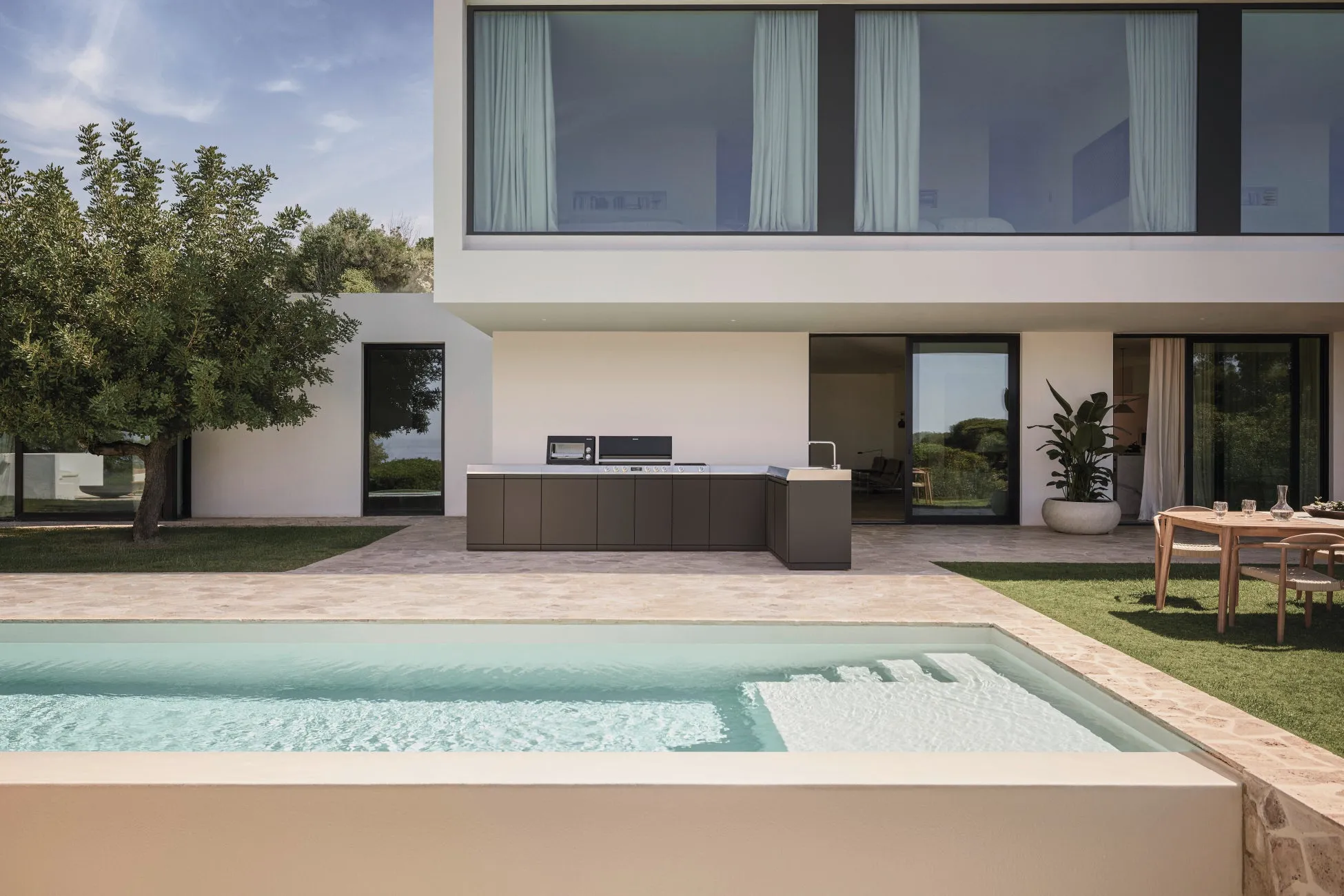 プールと屋外キッチンを備えたモダンな家の写真。