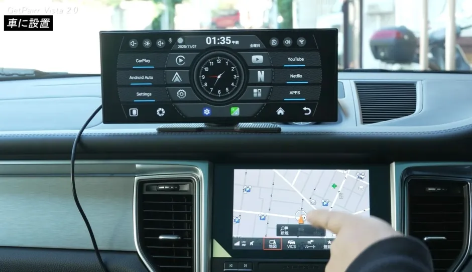 車のダッシュボードに設置されたカーナビゲーションシステム。上部には時刻やアプリへのショートカットが表示され、下部には地図が表示されている。